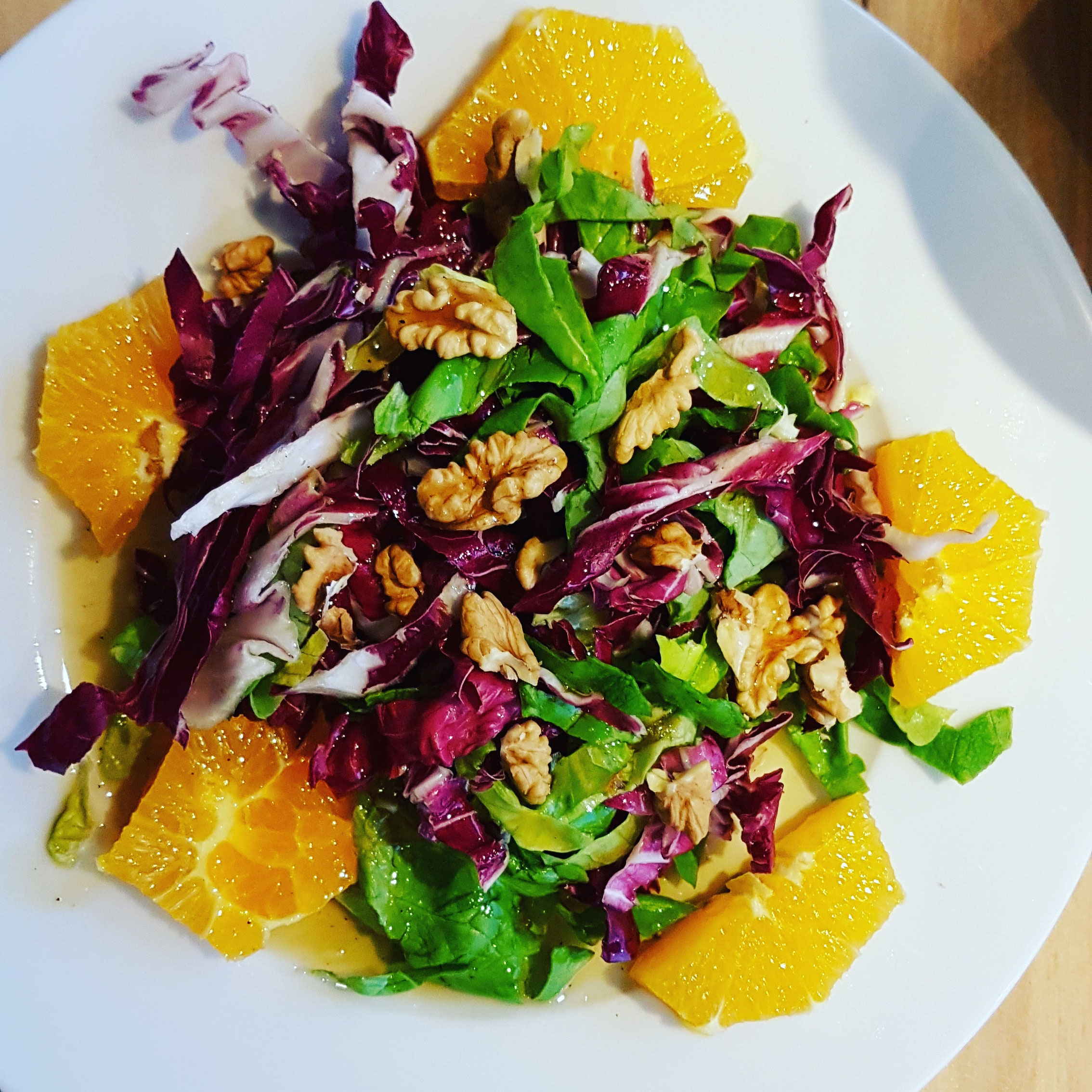 Bunter Salat auf Orangenfilets mit Walnüssen.