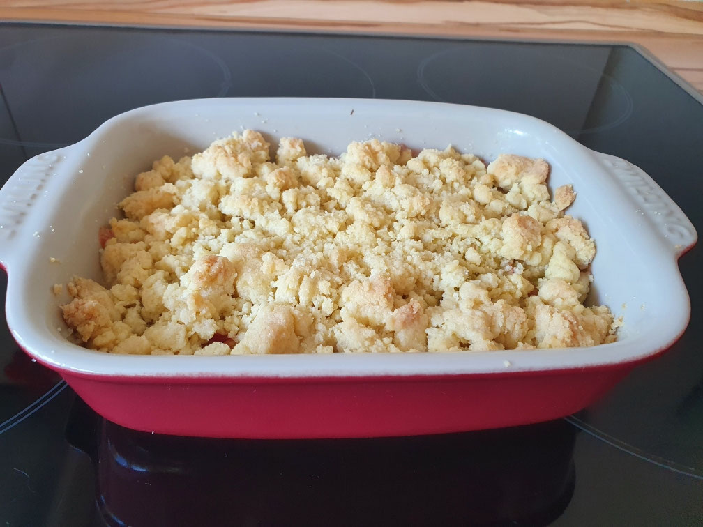 Gebackener Rhabarbercrumble mit goldenen Streuseln in der Auflaufform.