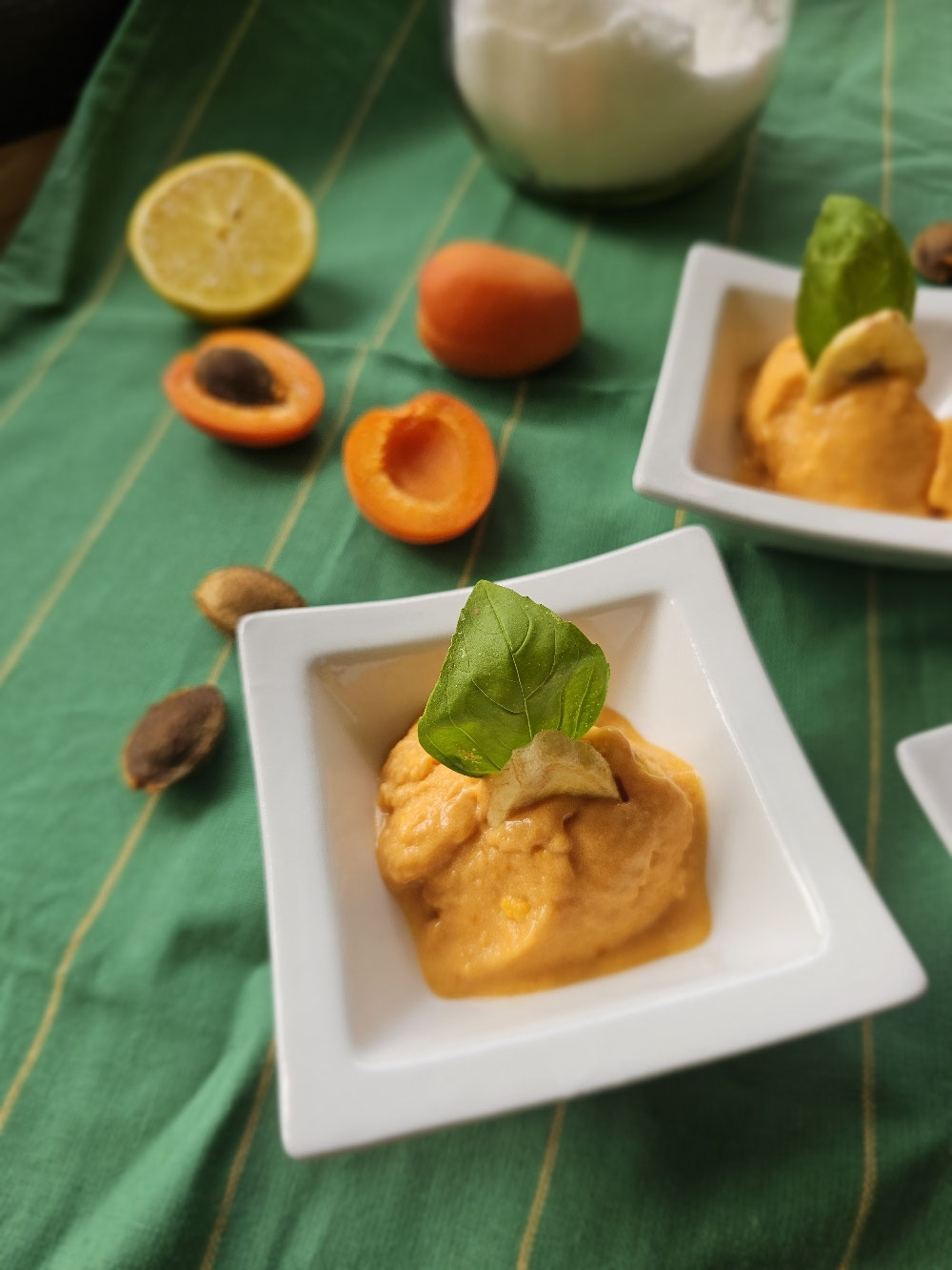 Aprikoseneis mit Joghurt in weißen Dessertschälchen.