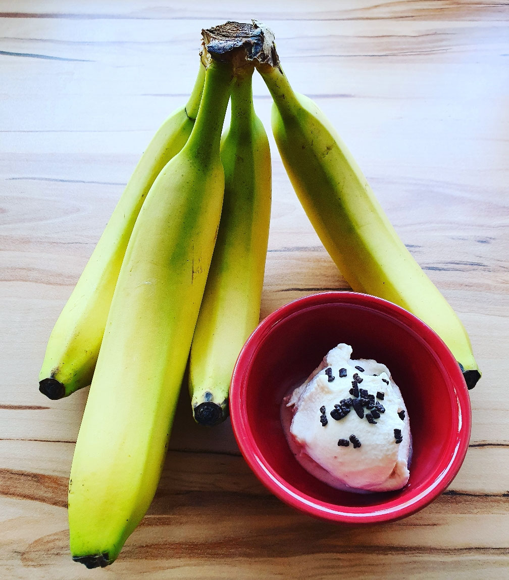 Bananeneis mit Schokostreuseln in einer roten Schale.
