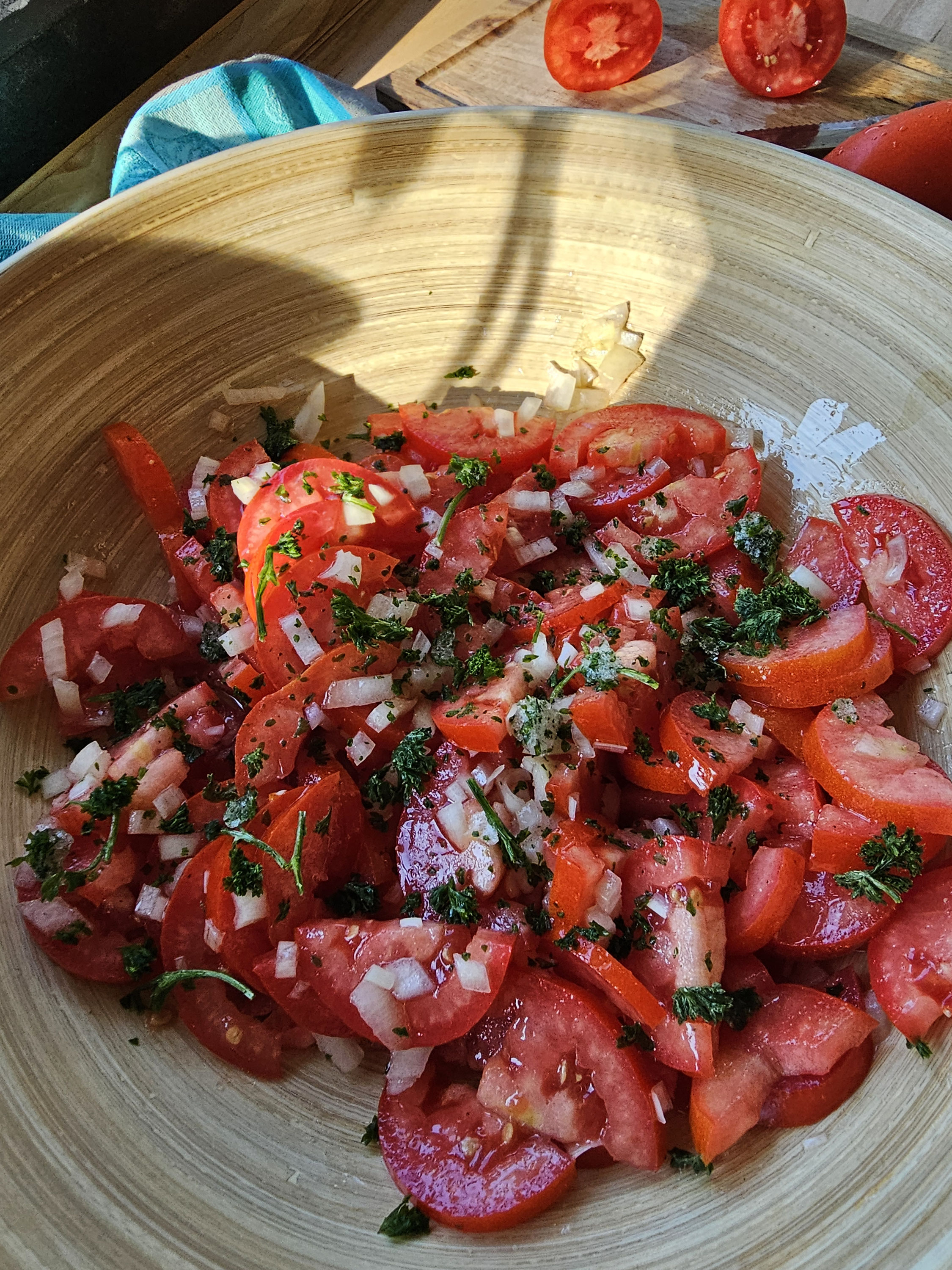 Tomatensalat mit Zwiebeln und Kräutern in einer Holzschüssel.