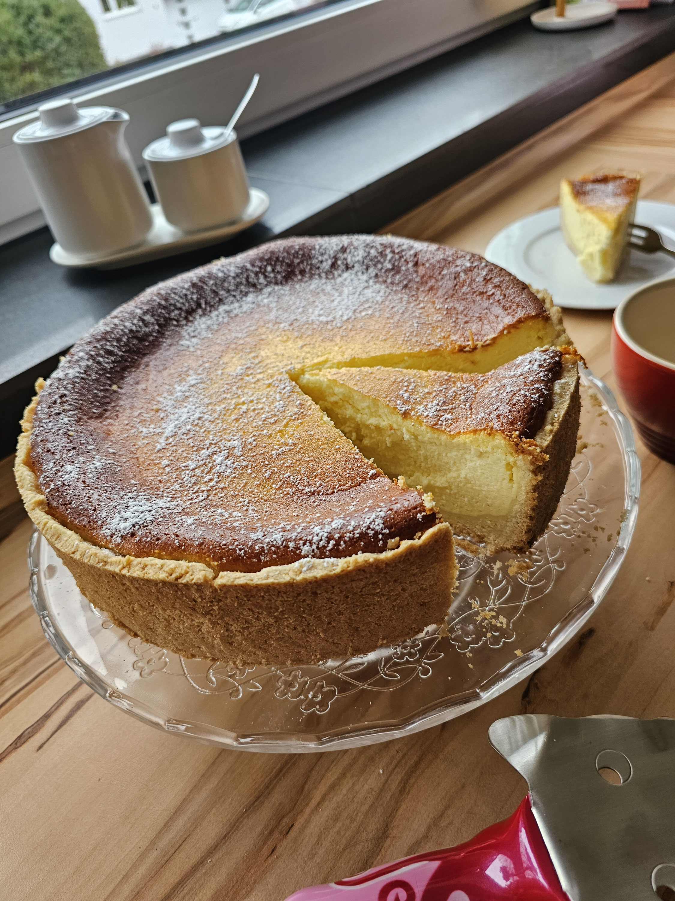 Angeschnittener Käsekuchen mit hoher Quarkfüllung und Mürbeteigboden.