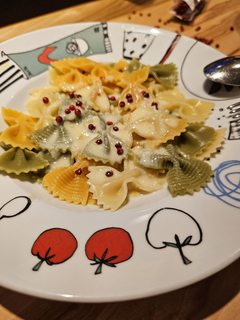Bunte Farfalle mit cremiger Vier-Käse-Sauce und roten Pfefferkörnern.