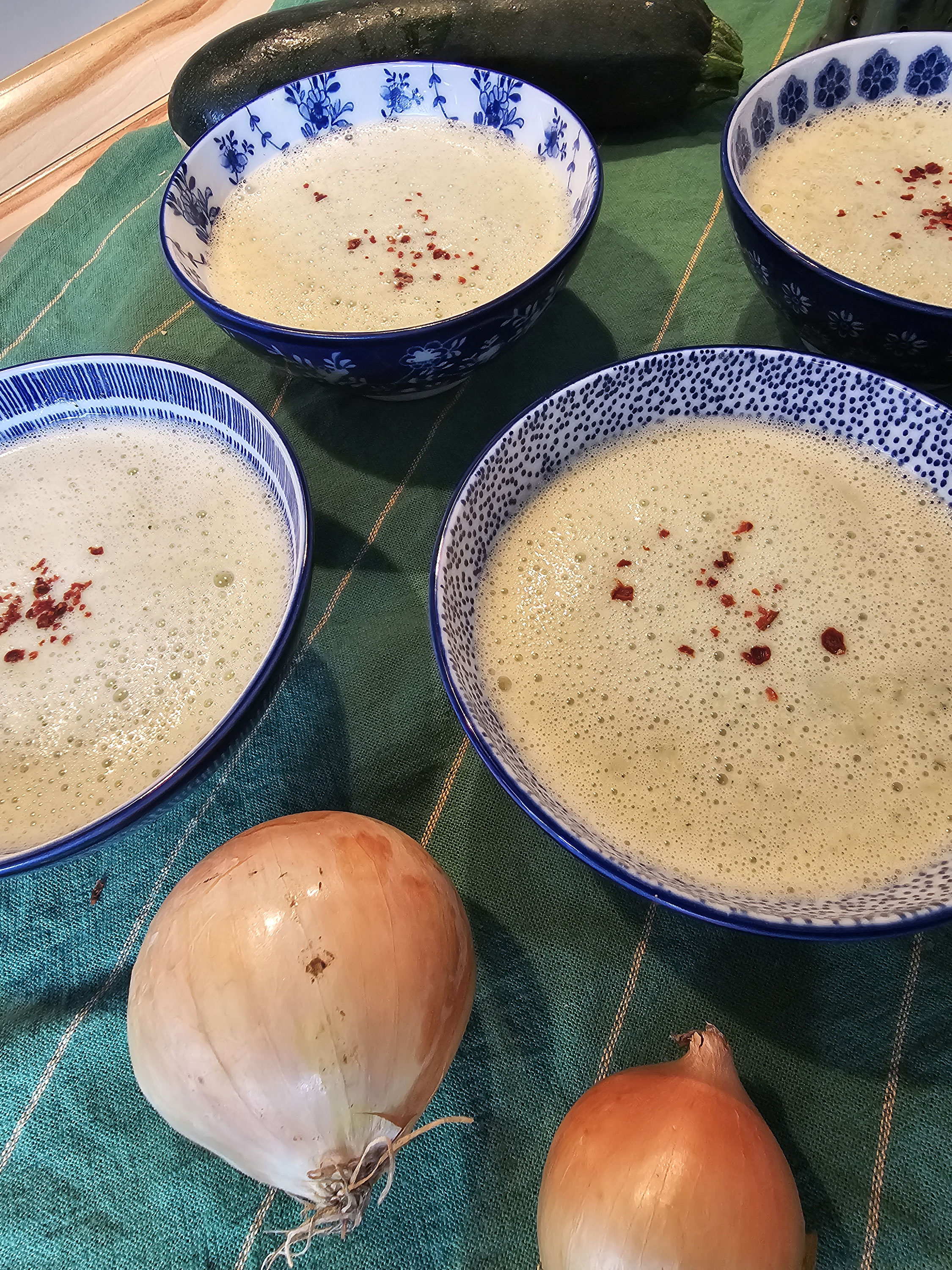 Schaumige Zucchinicremesuppe in blauen Schüsseln.