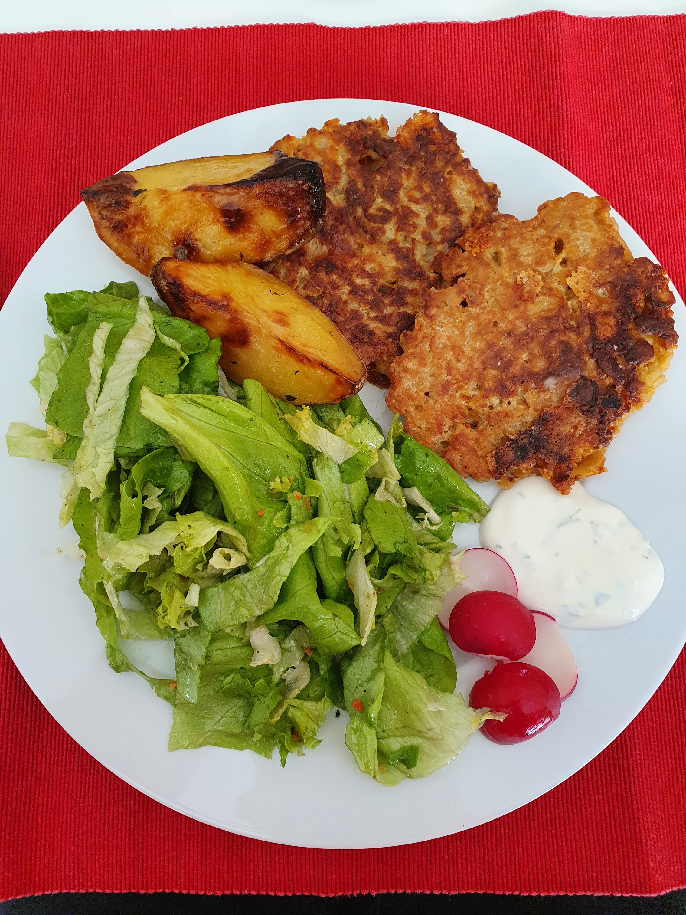 Goldbraune Haferflocken-Frikadellen mit grünem Salat und Radieschen.
