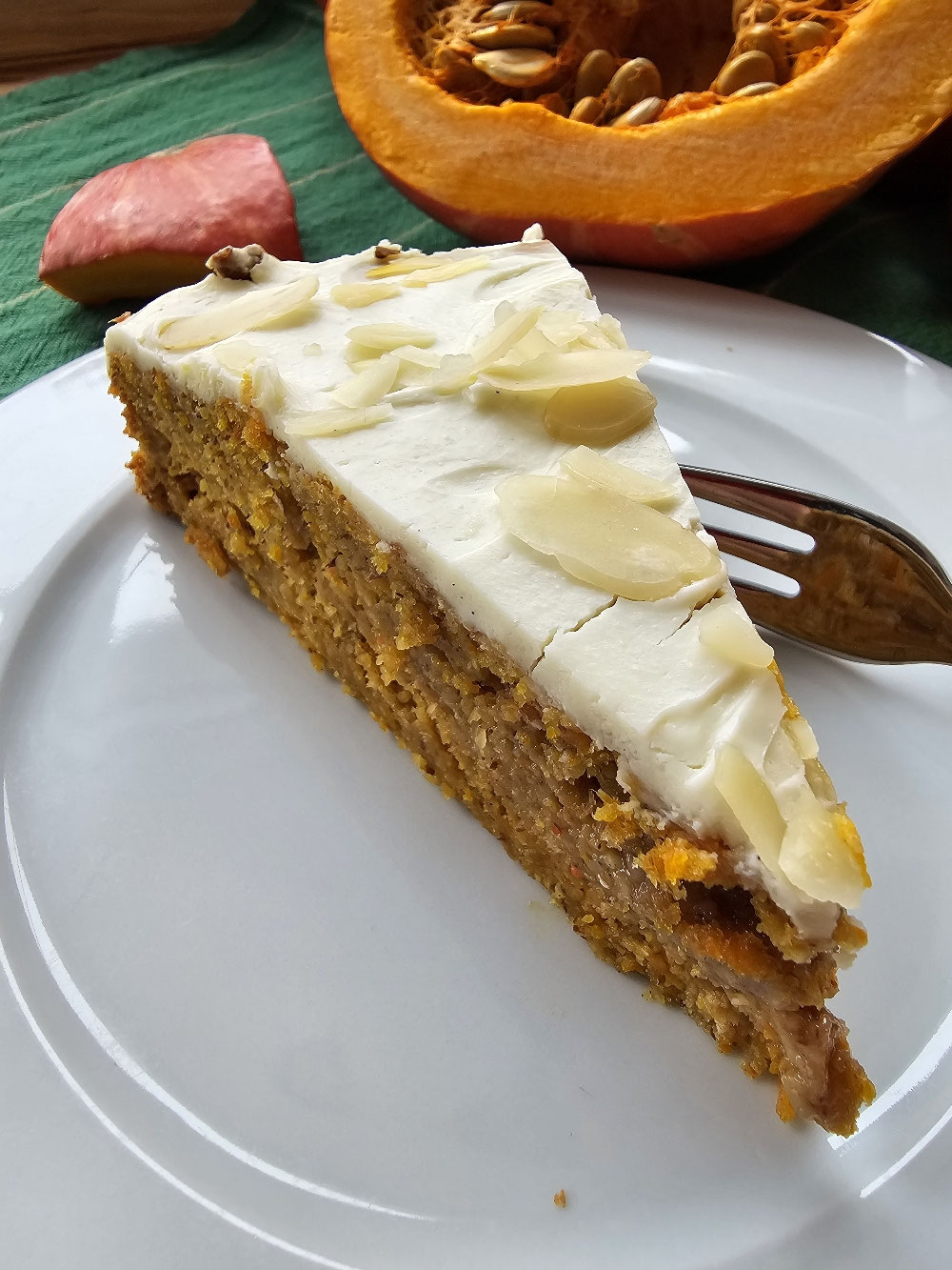 Saftiges Stück Kürbis-Apfelkuchen mit Frosting und Mandelblättchen.