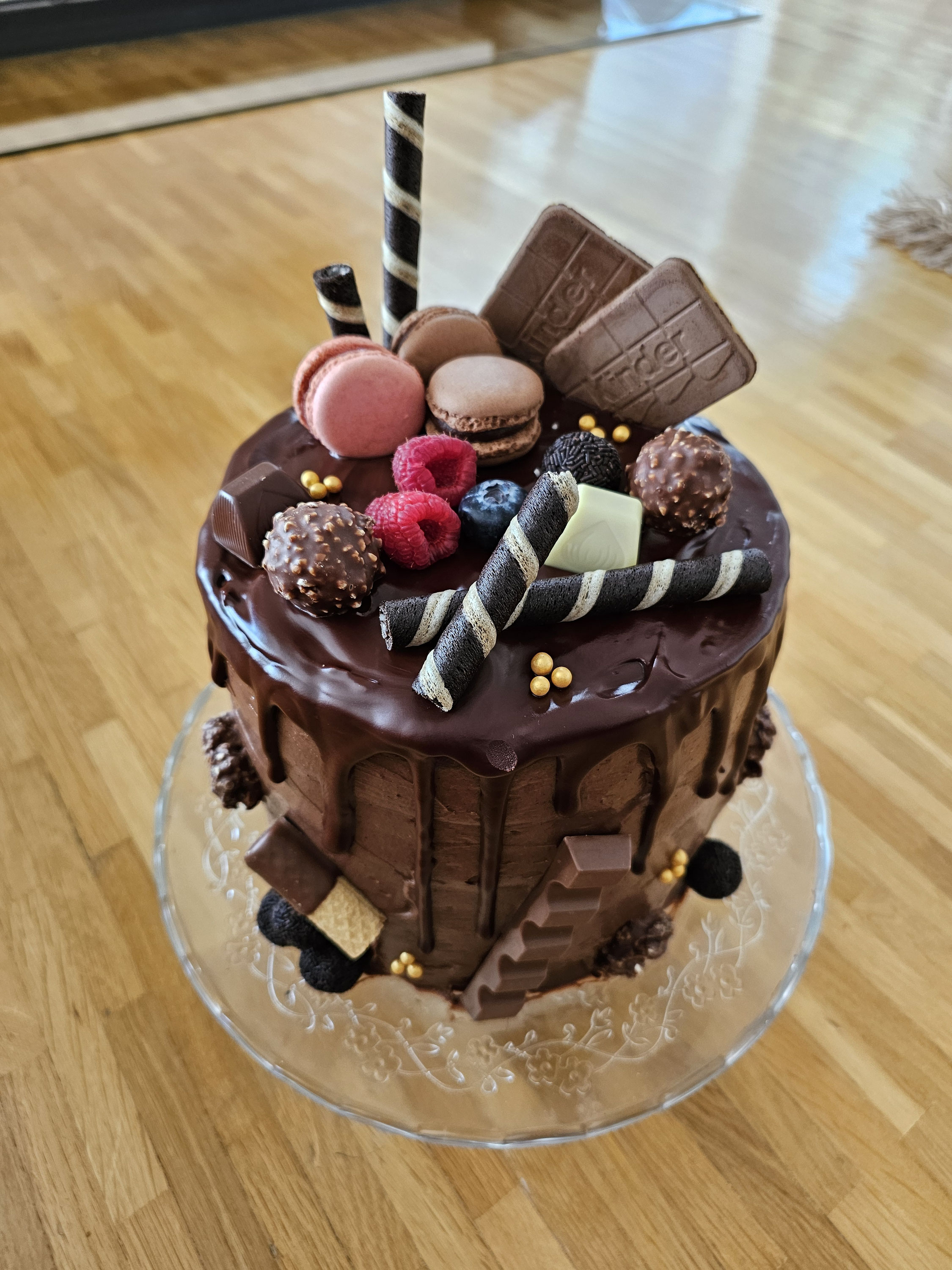 Hohe Nutella-Schokoladen-Torte mit Ganache, Beeren und Süßigkeiten dekoriert.