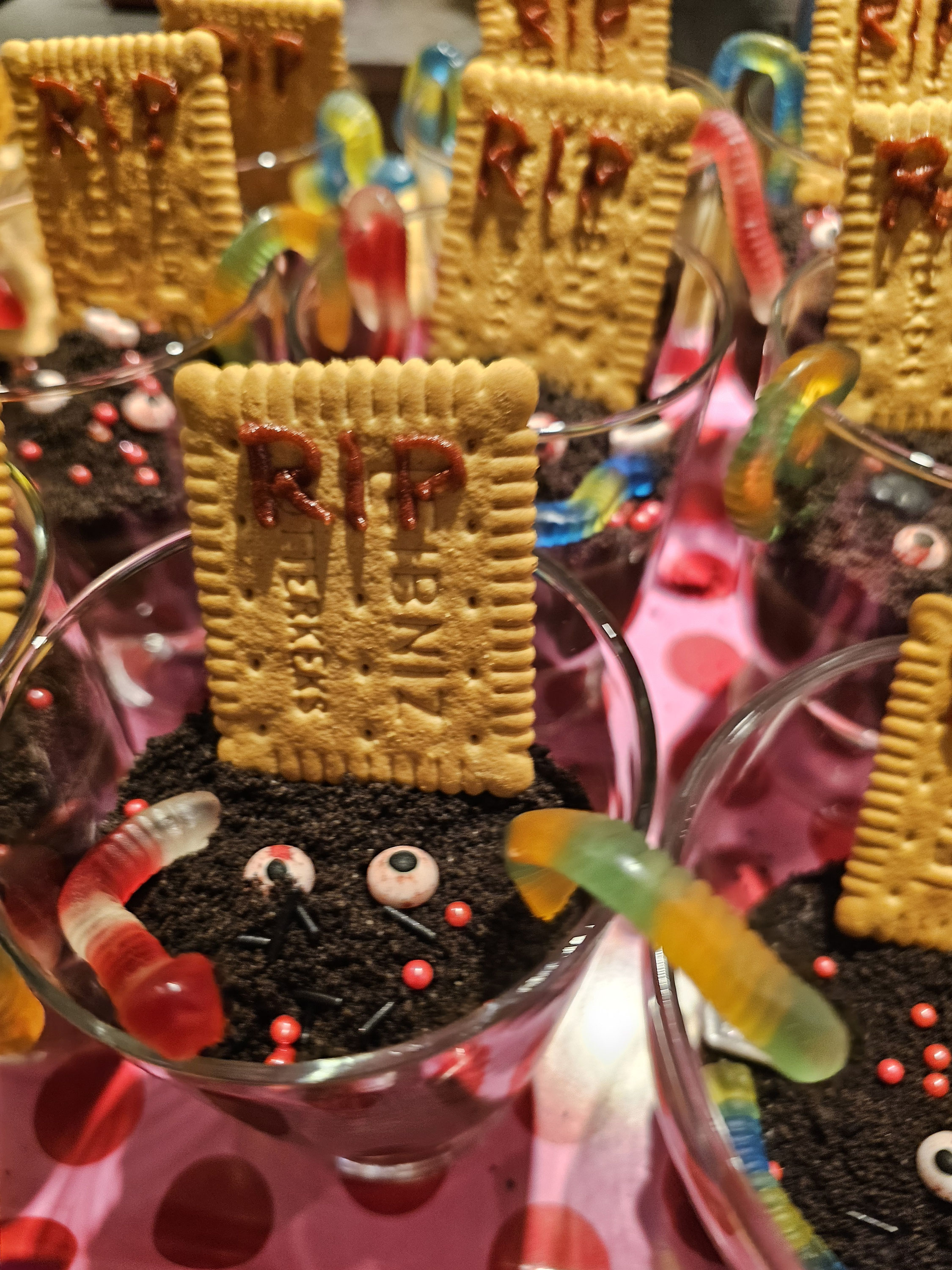 Halloween-Puddinggläser mit Keksgrabsteinen und Zuckeraugen.