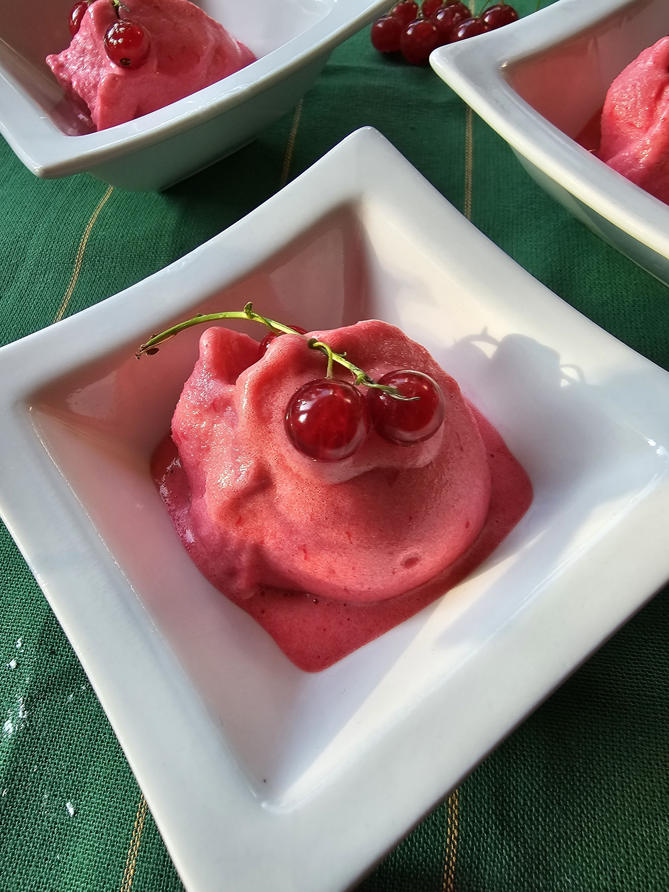 Cremiges rotes Johannisbeersorbet im weißen Dessertschälchen.