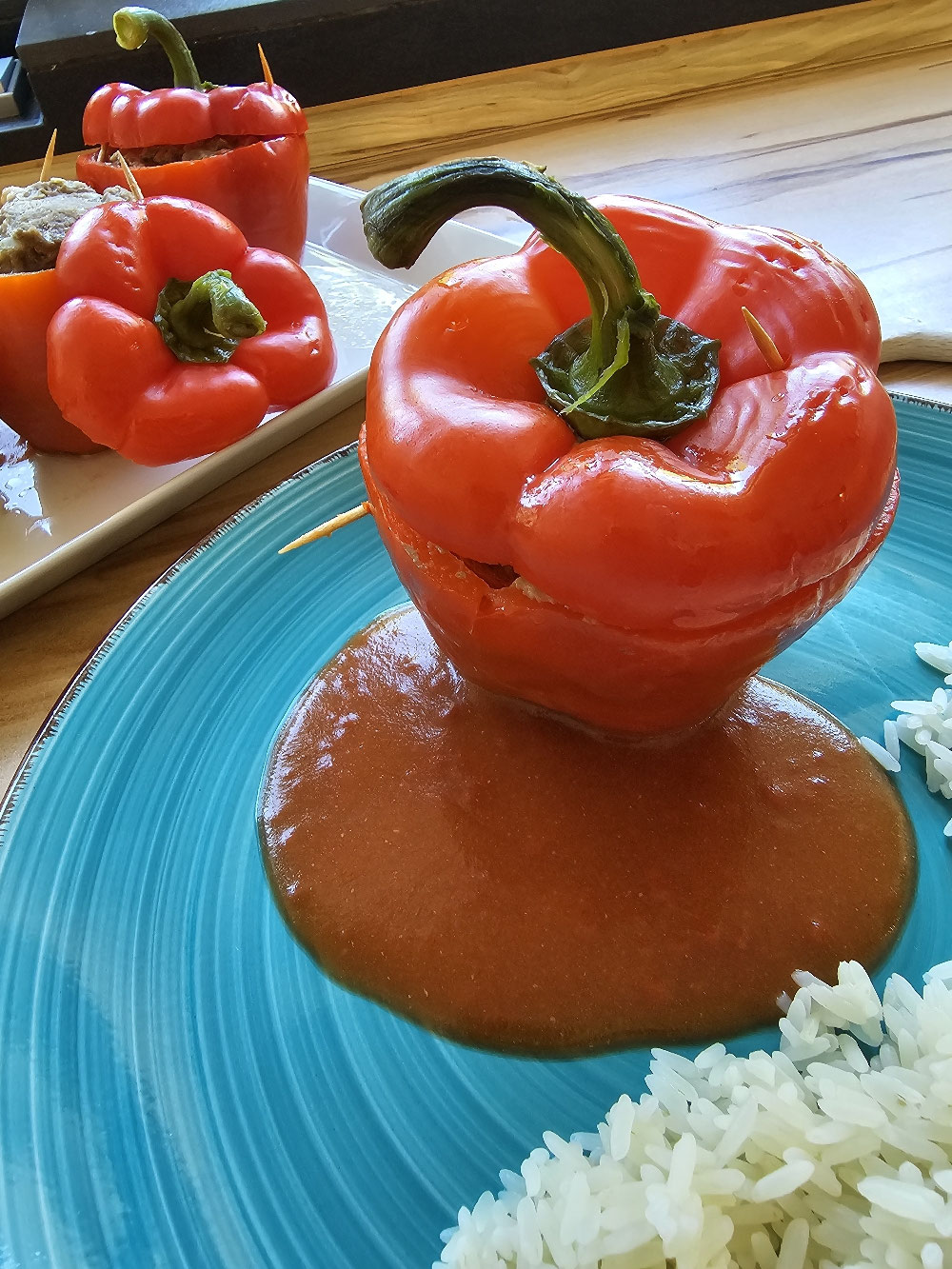 Gefüllte Paprika mit Tomatensauce auf einem blauen Teller.