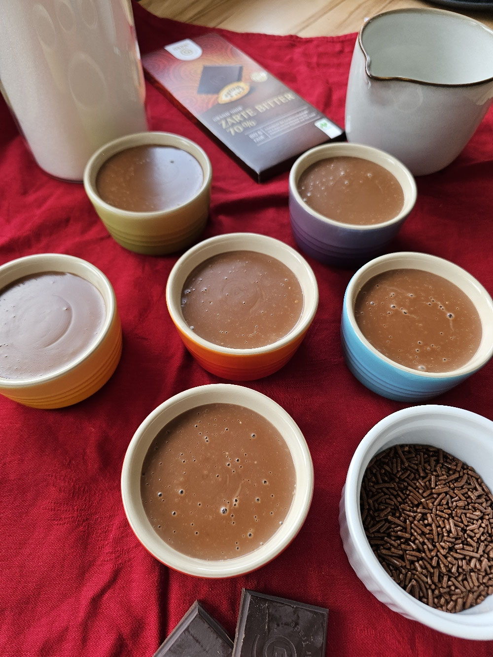 Selbstgemachter Schokoladenpudding in sechs bunten Schälchen.