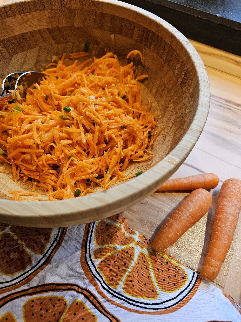 Frischer Karottensalat mit Schnittlauch in einer Holzschüssel.