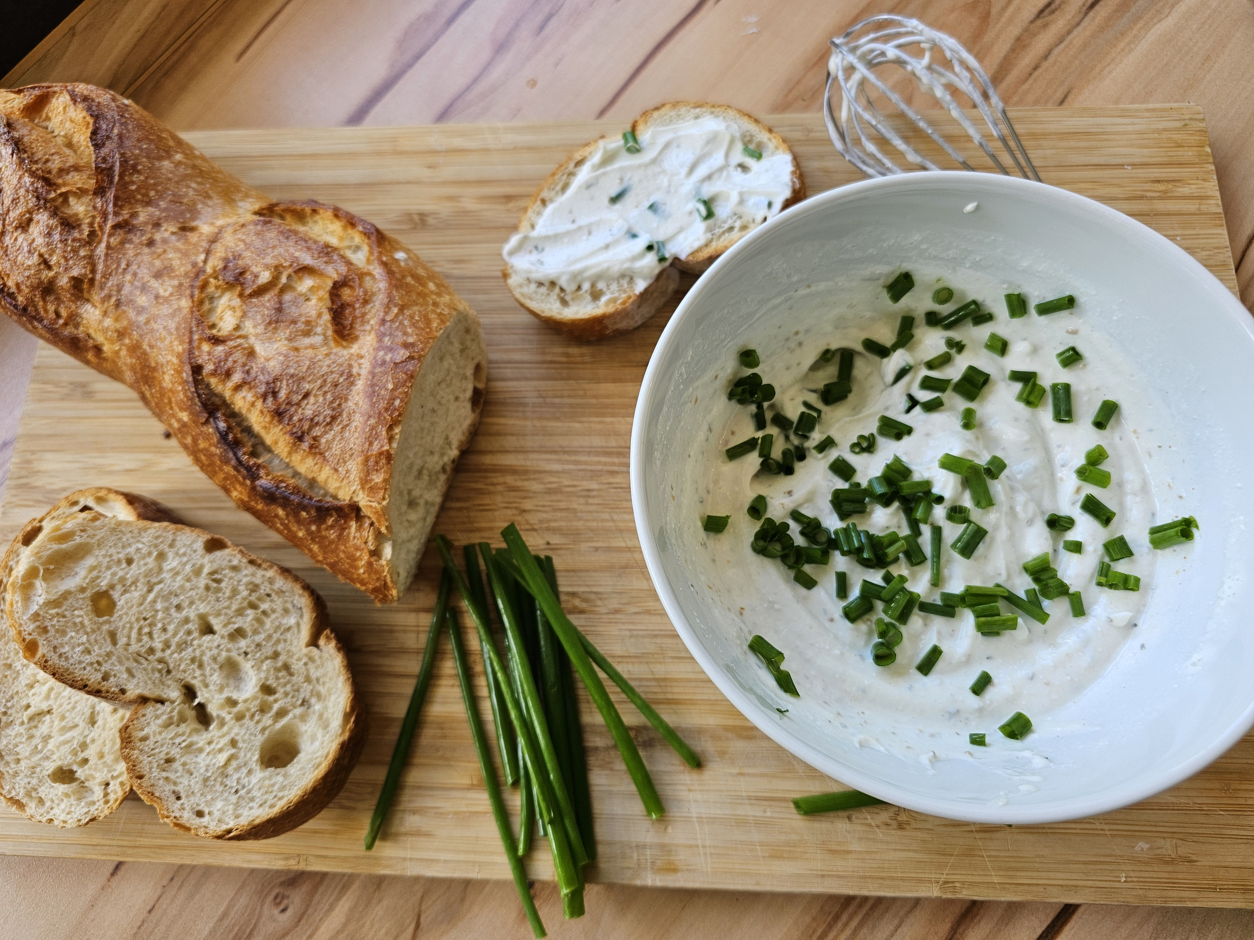 Frischer Kräuterquark in einer Schüssel mit Baguette.