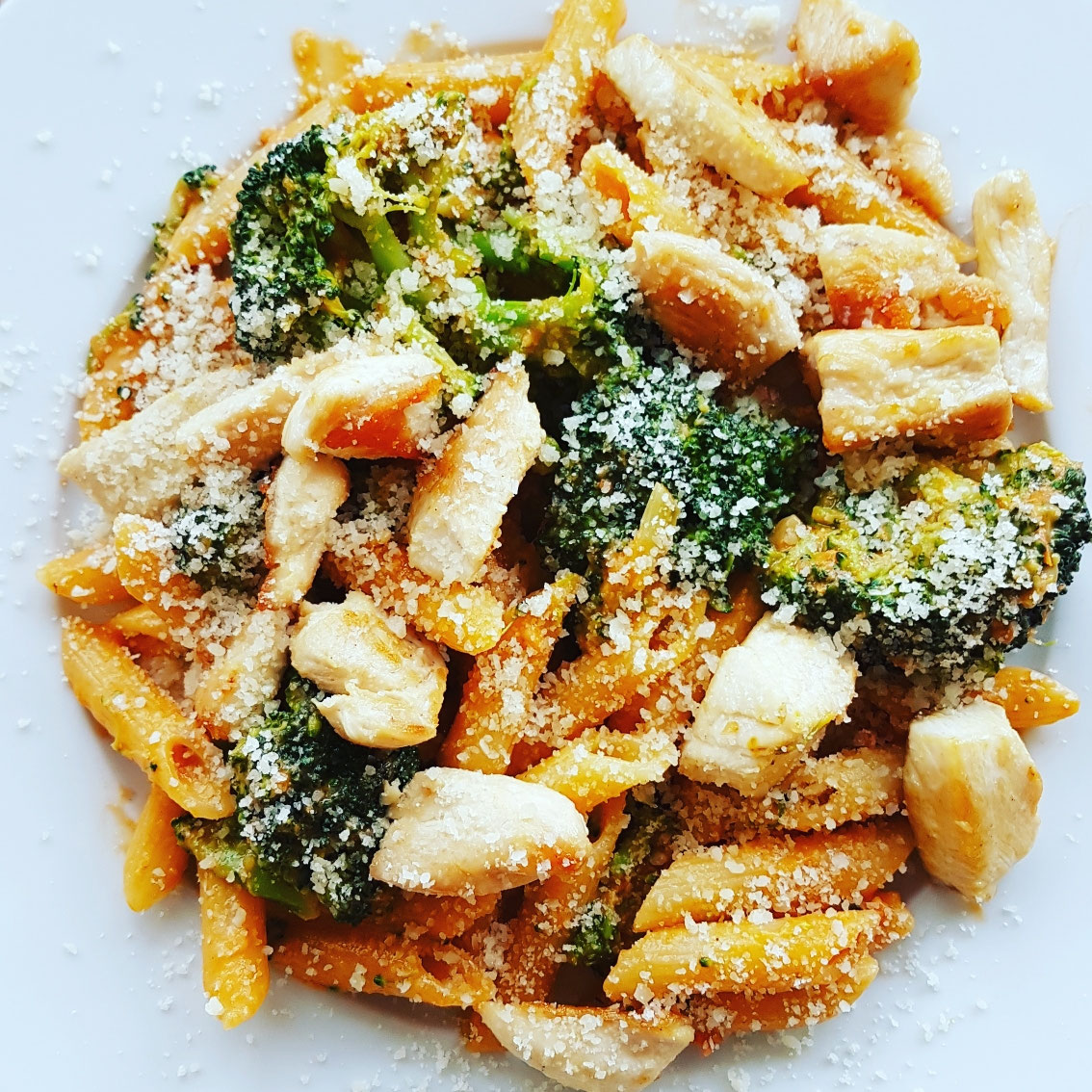 Hähnchenbruststreifen auf Tomaten-Broccoli-Penne mit Parmesan.