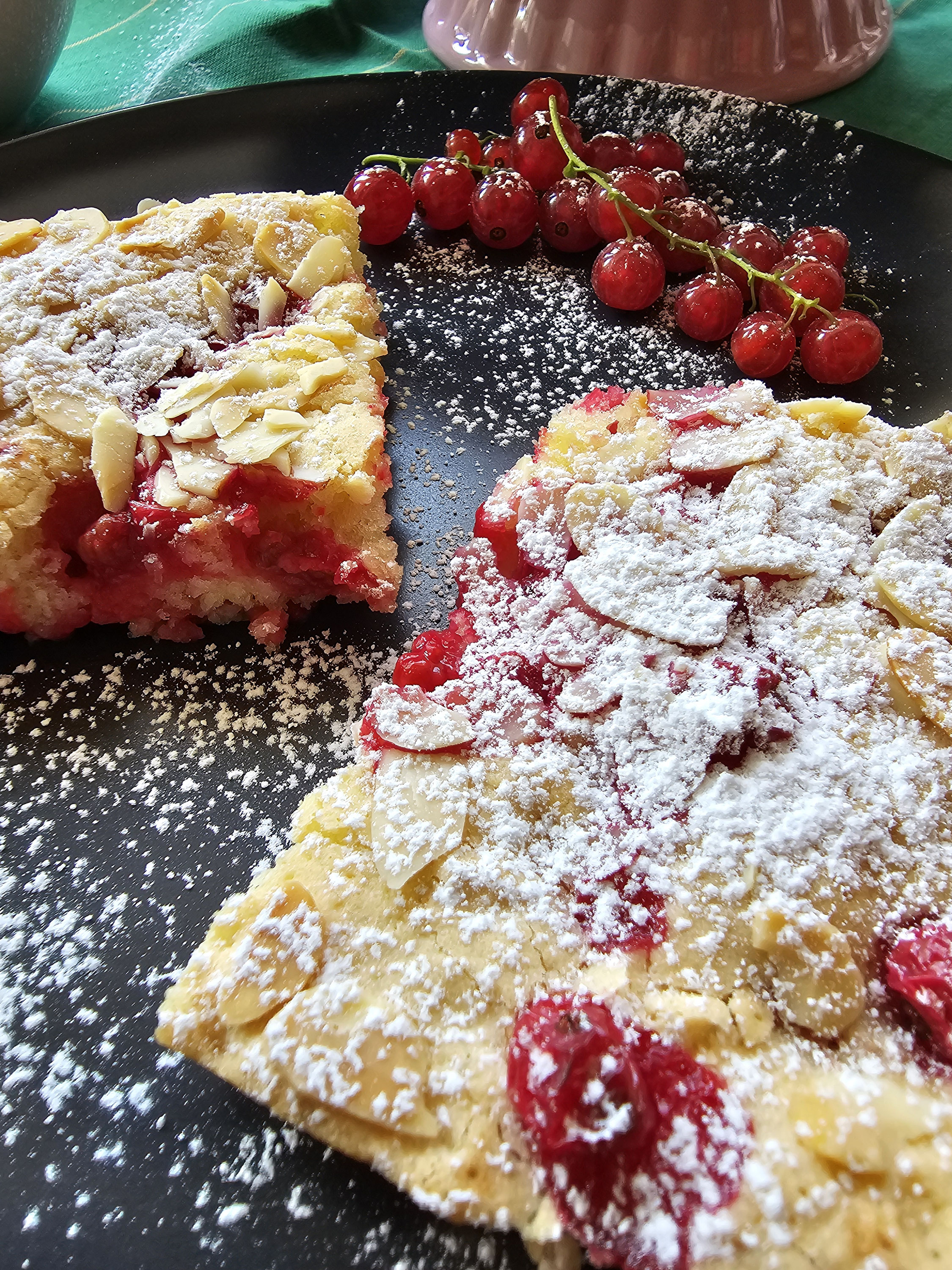 Johannisbeer-Blechkuchen mit Mandelblättchen und Puderzucker.