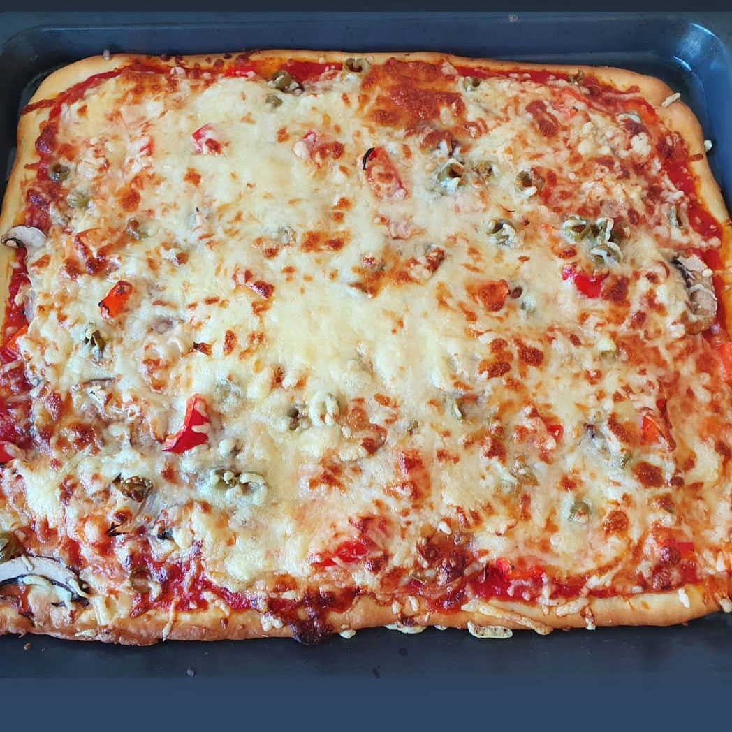 Goldbraune Ofenpizza auf dem Blech.