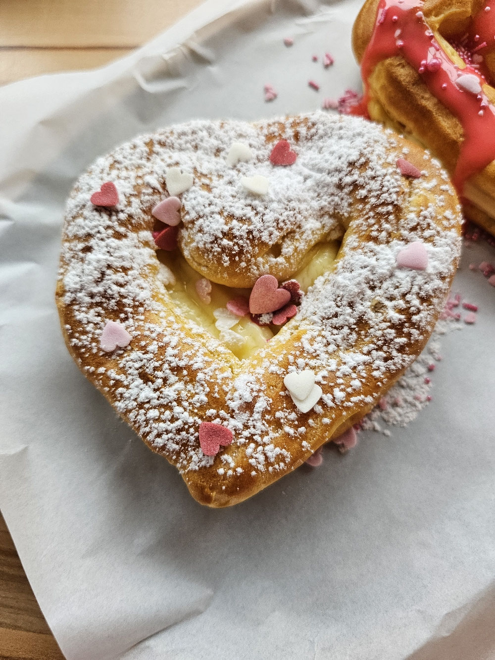 Herzförmiger Windbeutel mit Vanillefüllung und Puderzucker.