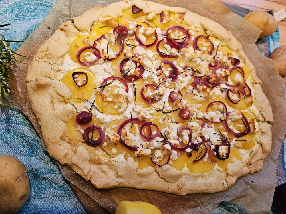 Goldbraune Kartoffelgalette mit roten Zwiebeln und Feta.