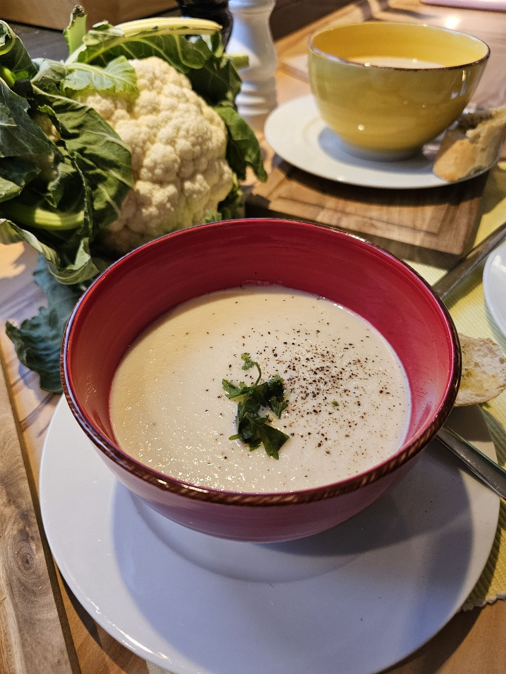 Cremige Blumenkohlsuppe in einer roten Schale.