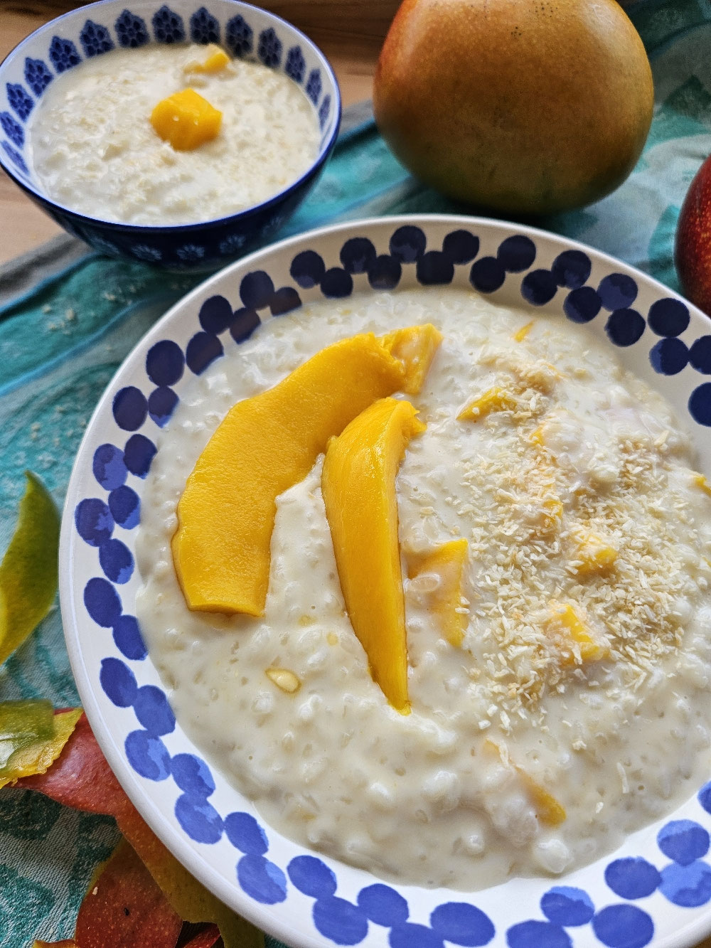 Cremiger Kokos-Mango-Milchreis mit Mangoscheiben und Kokos.